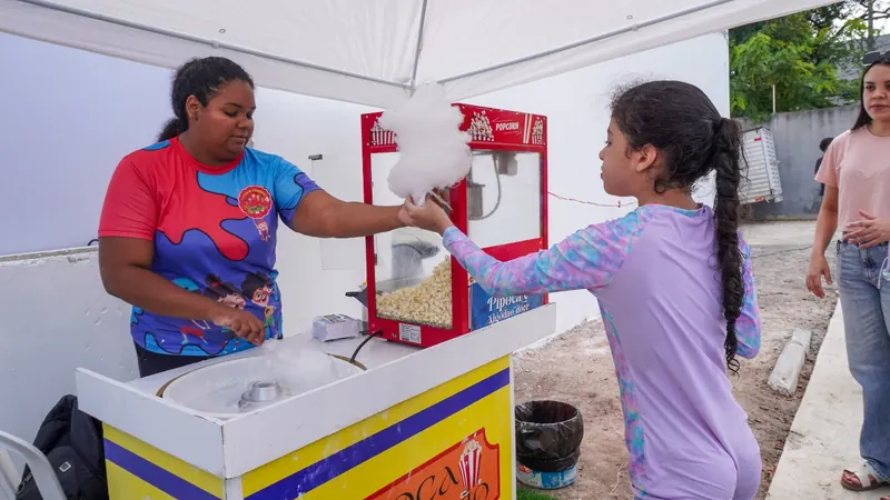 Voluntária entregando algodão-doce a uma menina durante ação social