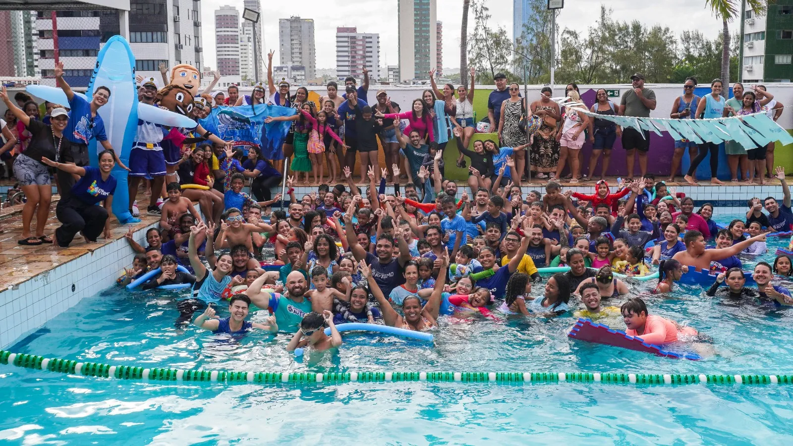 Dezenas de crianças e voluntários na piscina durante a Colônia de Férias