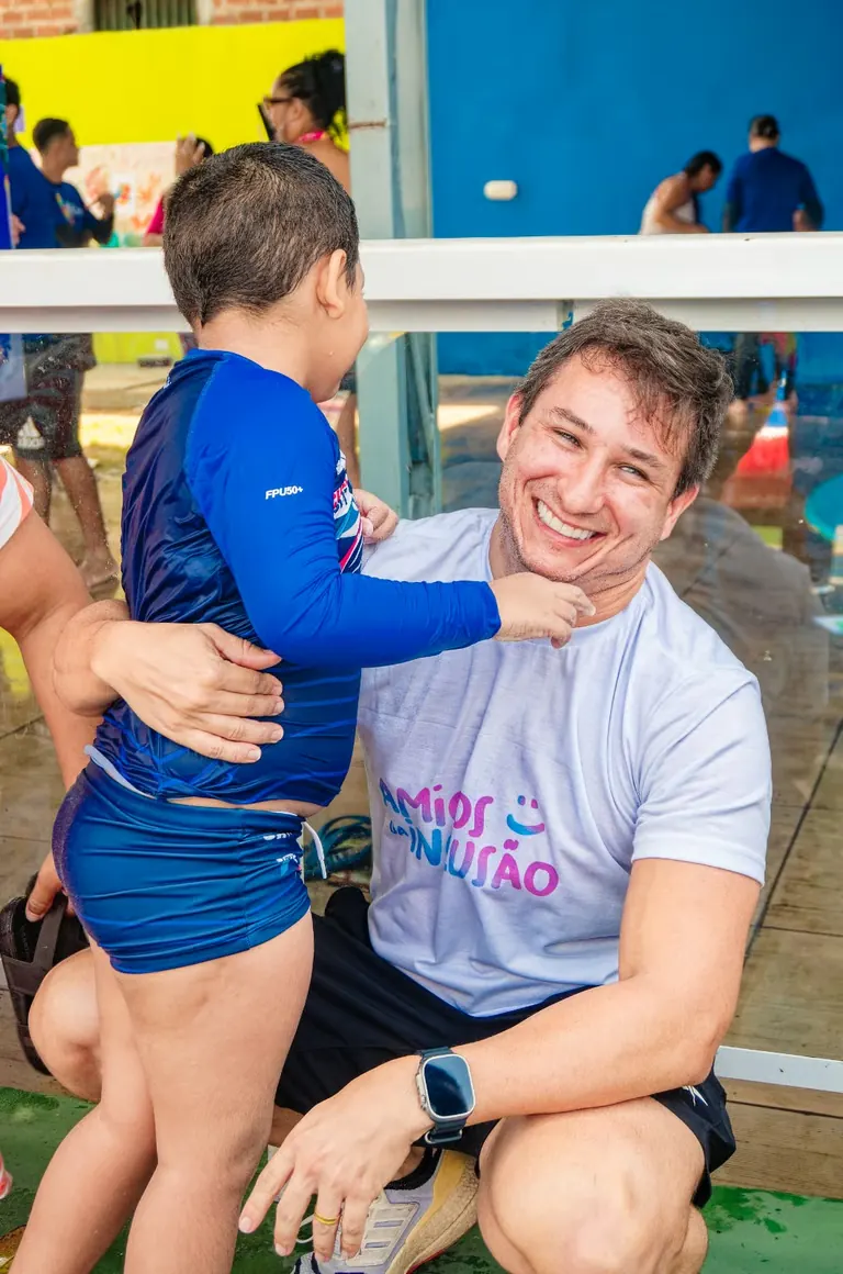 Kadu Lins, fundador da ONG, sorrindo com uma criança no colo durante atividade